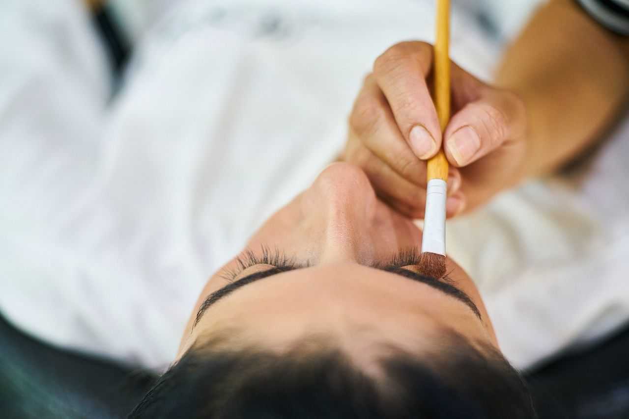 Close-up of person getting eyebrow makeup applied with brush.